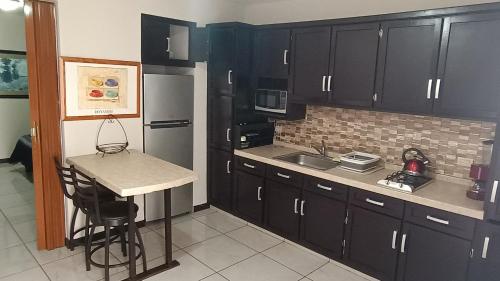 a kitchen with black cabinets and a small table in it at Suites Entrelagos in Ciudad Obregón
