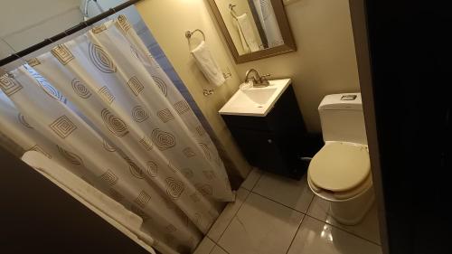 a bathroom with a toilet and a sink and a shower curtain at Suites Entrelagos in Ciudad Obregón