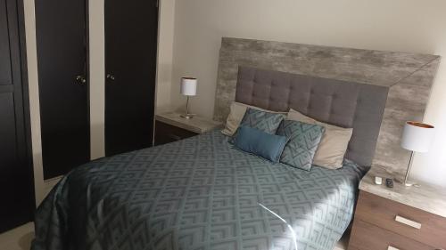 a bedroom with a large bed with blue pillows at Suites Entrelagos in Ciudad Obregón
