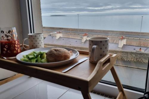 une assiette de nourriture sur une table à côté d'une fenêtre dans l'établissement Seaview cottage North Wales, à Penmaen-mawr