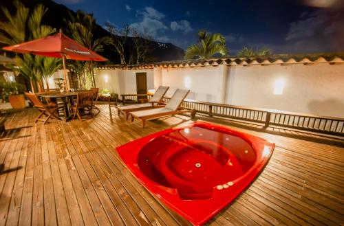 a red tub on a wooden deck with a table and umbrella at Cerro Tusa Glamping in Titiribí