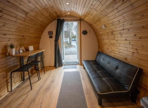 a leather couch in a room with a table and a window at Woodside Pod in Fort William