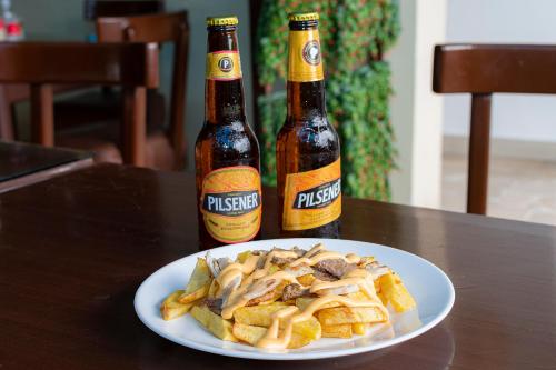 two bottles of beer and a plate of food on a table at Hotel de Alborada in Guayaquil