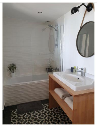 une salle de bain avec un lavabo, une baignoire et un miroir dans l'établissement Les pieds dans l’eau, à Fouesnant