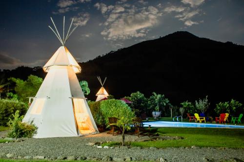 a white teepee in a garden with a pool at Cerro Tusa Glamping in Titiribí