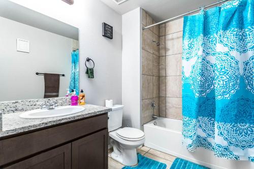 La salle de bains est pourvue d'un rideau de douche bleu et de toilettes. dans l'établissement Texas style 3BR 3BA Home w 12 Arcade Games & HotTub- 5mins to Airport w Private Garage, à San Antonio