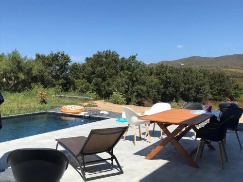 eine Terrasse mit einem Tisch und Stühlen neben einem Pool in der Unterkunft Villa Isula Contemporaine Piscine chauffée in Palasca