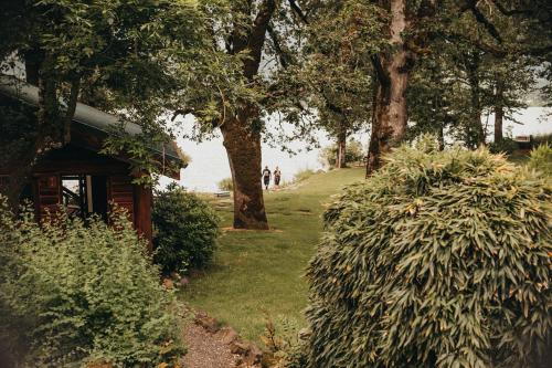 a garden with trees and a house and a bush at Wilder and Pine Riverside Cabins in Stevenson