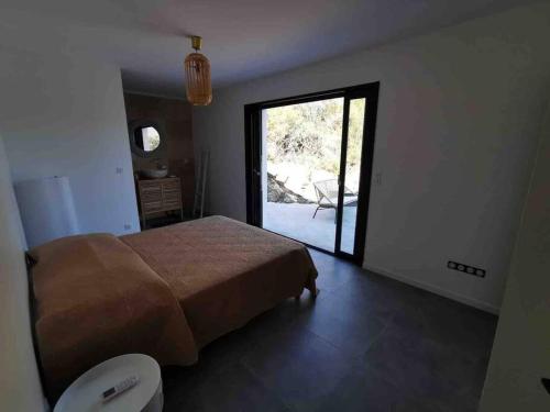 1 dormitorio con 1 cama y puerta que da a un patio en Villa Isula Contemporaine Piscine chauffée, en Palasca
