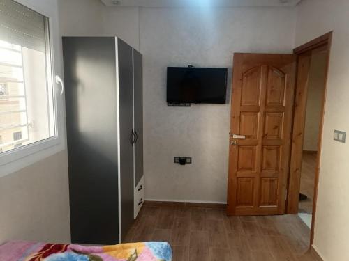 een kamer met een deur en een televisie aan een muur bij hay adrar 2 agadir Morocco in Agadir