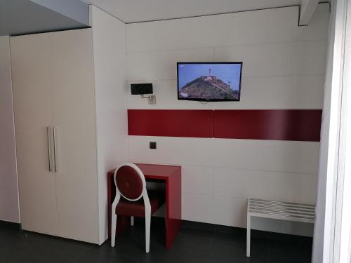 Habitación con silla y TV en la pared. en Hotel Oceano, en Nazaré