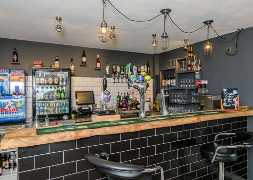 a bar with two stools and a counter with drinks at Castle Brake Holiday Park in Woodbury