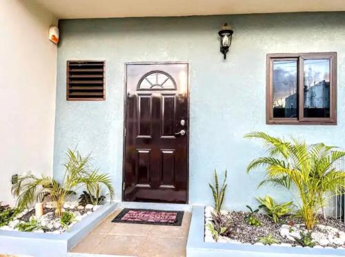 a front door of a house with palm trees at Wynters'Escape-gated 1 or 2 Bedroom w PuertoSecoBeach access in Discovery Bay