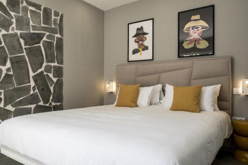 Un dormitorio con una gran cama blanca con cuadros en la pared. en Casa Saidera, en Playa Blanca