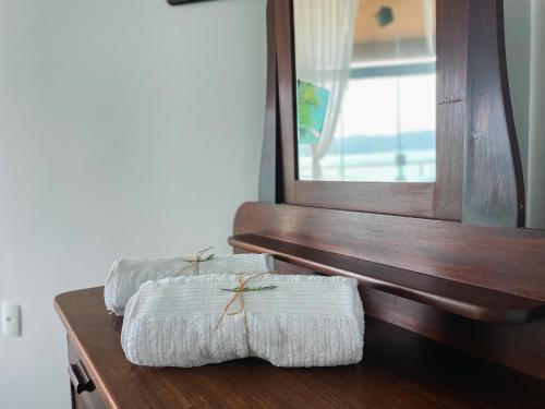 two towels sitting on a wooden counter in front of a mirror at Casa pé na areia para até 14 pessoas em bombinhas in Bombinhas