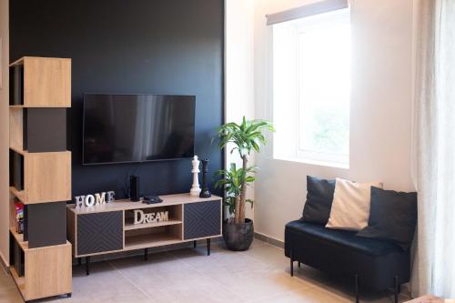 a living room with a flat screen tv and a chair at Live the Local Life , Old Town Kos in Kos Town