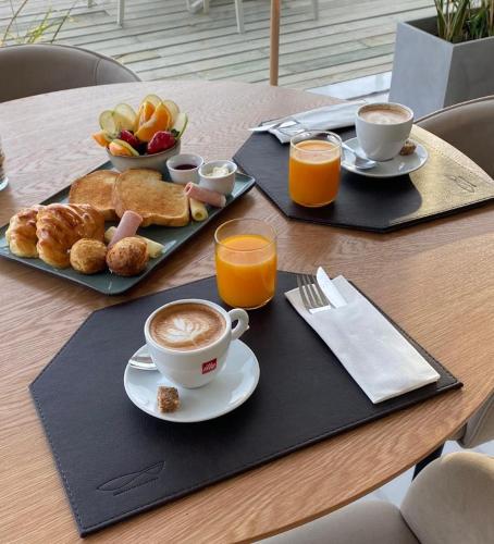 a table with a breakfast of coffee and croissants and fruit at SYRAH Premium B1 - Vistas al Parque by depptö in Punta del Este