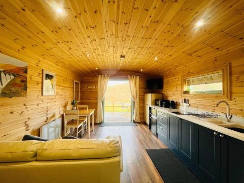 eine Küche mit Holzwänden und ein Sofa in einem Zimmer in der Unterkunft Hwyl in Abbey-Cwmhir