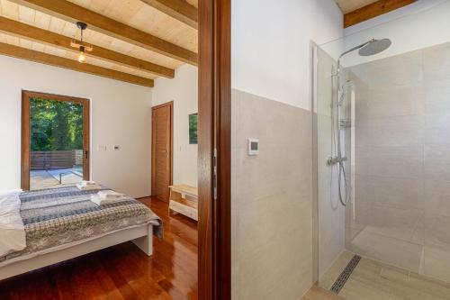 - une chambre avec un lit et une douche en verre dans l'établissement Villa David - luxurious secluded villa with a heated pool, à Butkovići