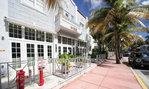 a red fire hydrant on a sidewalk in front of a building at The Julia Hotel in Miami Beach