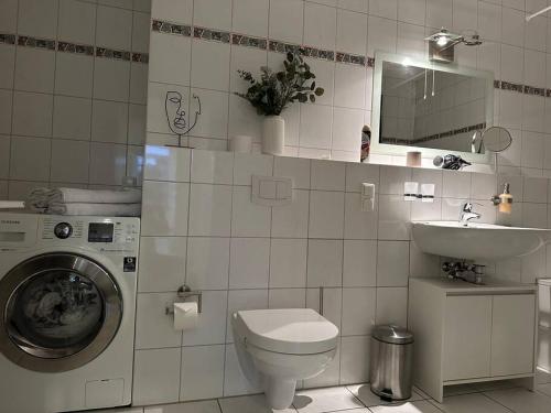 a bathroom with a toilet and a sink and a washing machine at MORINA Residences in Mainz