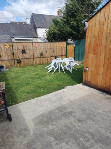 a yard with two white tables and a fence at chalet avec jardin proche du Mont Saint Michel in Pontorson