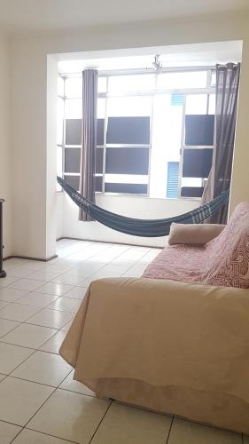 a bedroom with a hammock in a room with a window at Pé na areia Gonzaguinha São Vicente in São Vicente