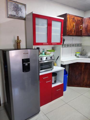kuchnia z czerwonymi szafkami i lodówką ze stali nierdzewnej w obiekcie Nice private apartment studio to discover CR w mieście Alajuela