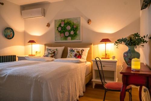 1 dormitorio con 1 cama y 1 mesa con 2 lámparas en Nomad Rooms, en Mostar