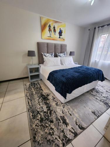 a bedroom with a large bed with a blue blanket at 2a - 64 No load shedding 2bed 2bath with garden in Centurion