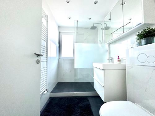 a white bathroom with a sink and a toilet at Stilvolles Apartment in Bonn in Bonn