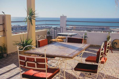 a table and chairs on a balcony with a view of the ocean at Adrenalin Surf House in Tamraght Ouzdar
