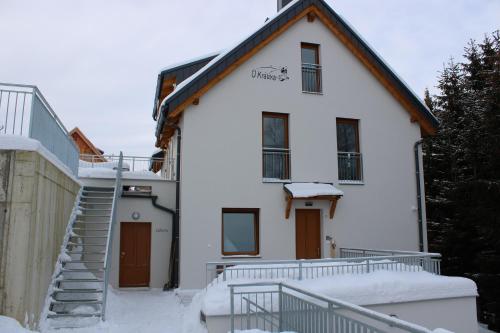 une maison blanche avec de la neige sur les escaliers dans l'établissement U Králíka, apartmán E, à Dolní Morava