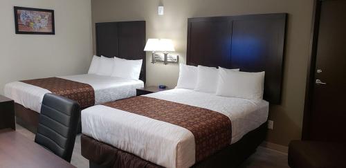 a hotel room with two beds with white sheets at Econo Lodge Umatilla Columbia River Area in Umatilla