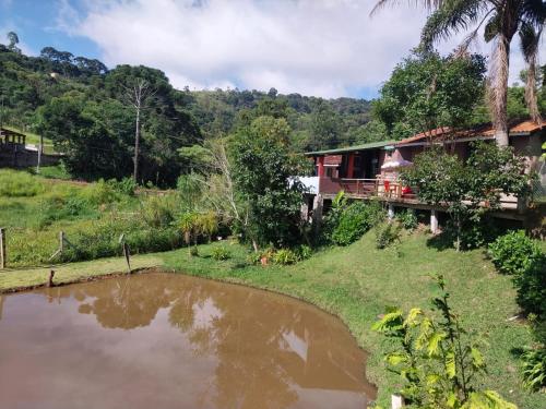 a house with a pond in front of it at Pousada Beija flor in Extrema