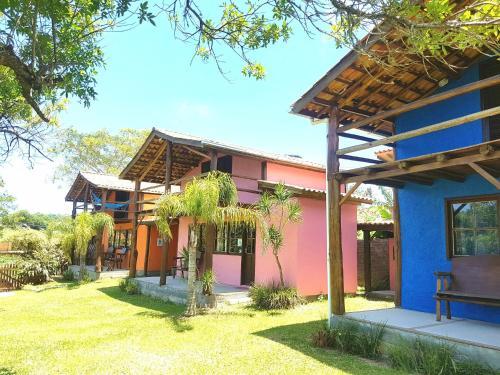 una casa rosa y azul con un patio de césped en Rosatrip Surf Bungalows, en Praia do Rosa