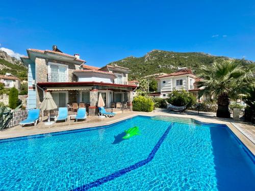 a swimming pool in front of a house with a shark in the water at Family-Friendly 4 BR Villa with Pool and Garden - Fethiye in Fethiye