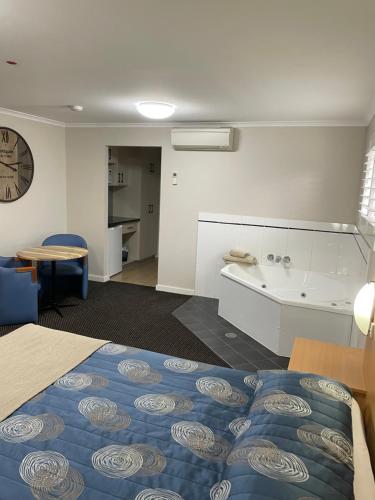 a room with a bed and a tub and a sink at Cattlemans Country Motor Inn & Serviced Apartments in Dubbo