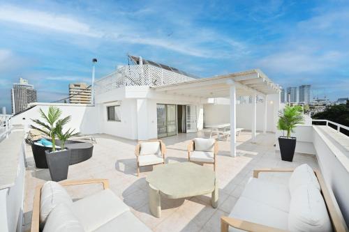 um pátio com mobiliário branco no telhado em Lovely Penthouse by HolyGuest em Tel Aviv