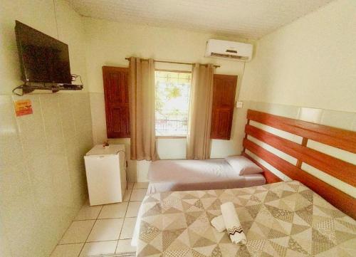 a bedroom with two beds and a television and a window at POUSADA FLORA in Alter do Chao
