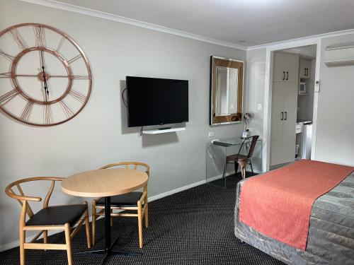 a hotel room with a bed and a table and a clock at Cattlemans Country Motor Inn & Serviced Apartments in Dubbo