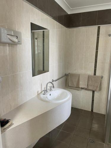 a bathroom with a sink and a mirror at Cattlemans Country Motor Inn & Serviced Apartments in Dubbo