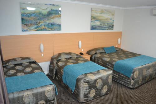 a hotel room with two beds and two chairs at Cattlemans Country Motor Inn & Serviced Apartments in Dubbo