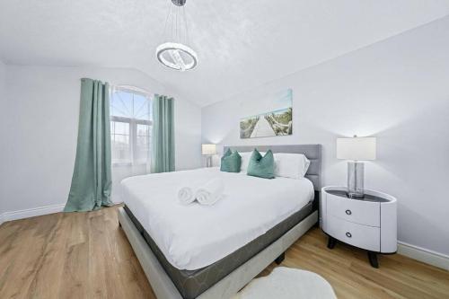 a white bedroom with a large bed with green curtains at Stylish & Cozy - 4Bdrm House Fast WIFI, 2.5 Bath in Barrie