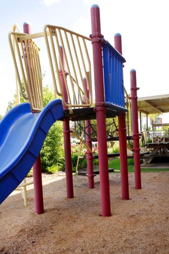 a playground with a blue slide and two chairs at Cattlemans Country Motor Inn & Serviced Apartments in Dubbo