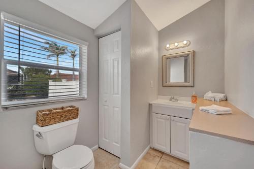 a bathroom with a toilet and a sink and a window at Sunny Sanctuary in Marco Island