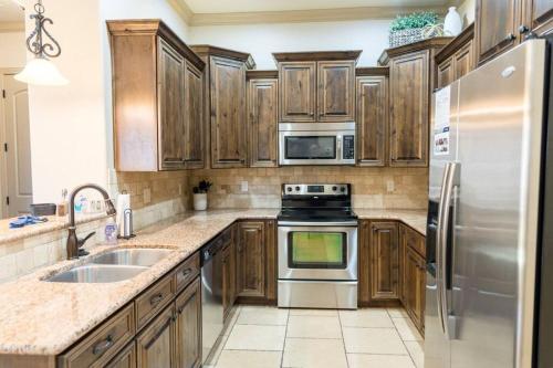 a kitchen with wooden cabinets and a stainless steel refrigerator at Suite Retreat with Pool Spa Gym and Tennis Court in Hurricane