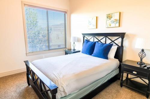 a bedroom with a bed with blue pillows and a window at Suite Retreat with Pool Spa Gym and Tennis Court in Hurricane
