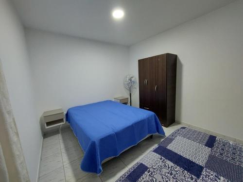 1 dormitorio con 1 cama azul y armario de madera en El descanso en Santa Rosa