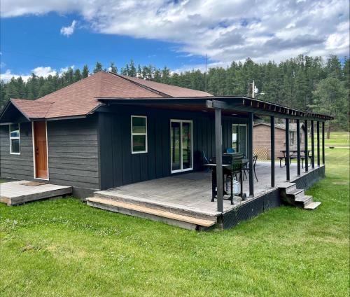 a house with a deck with a table on it at Cabin 12 at Horse Creek Resort in Rapid City